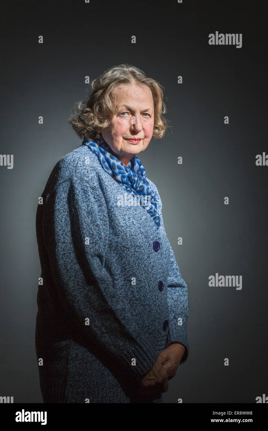 Portrait of senior woman standing with hands clasped against gray background Stock Photo