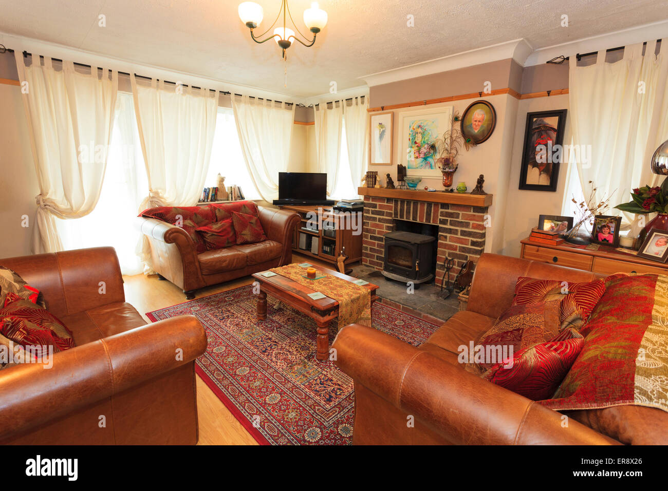 Lounge in english house with three leather sofas and wood burner Stock Photo