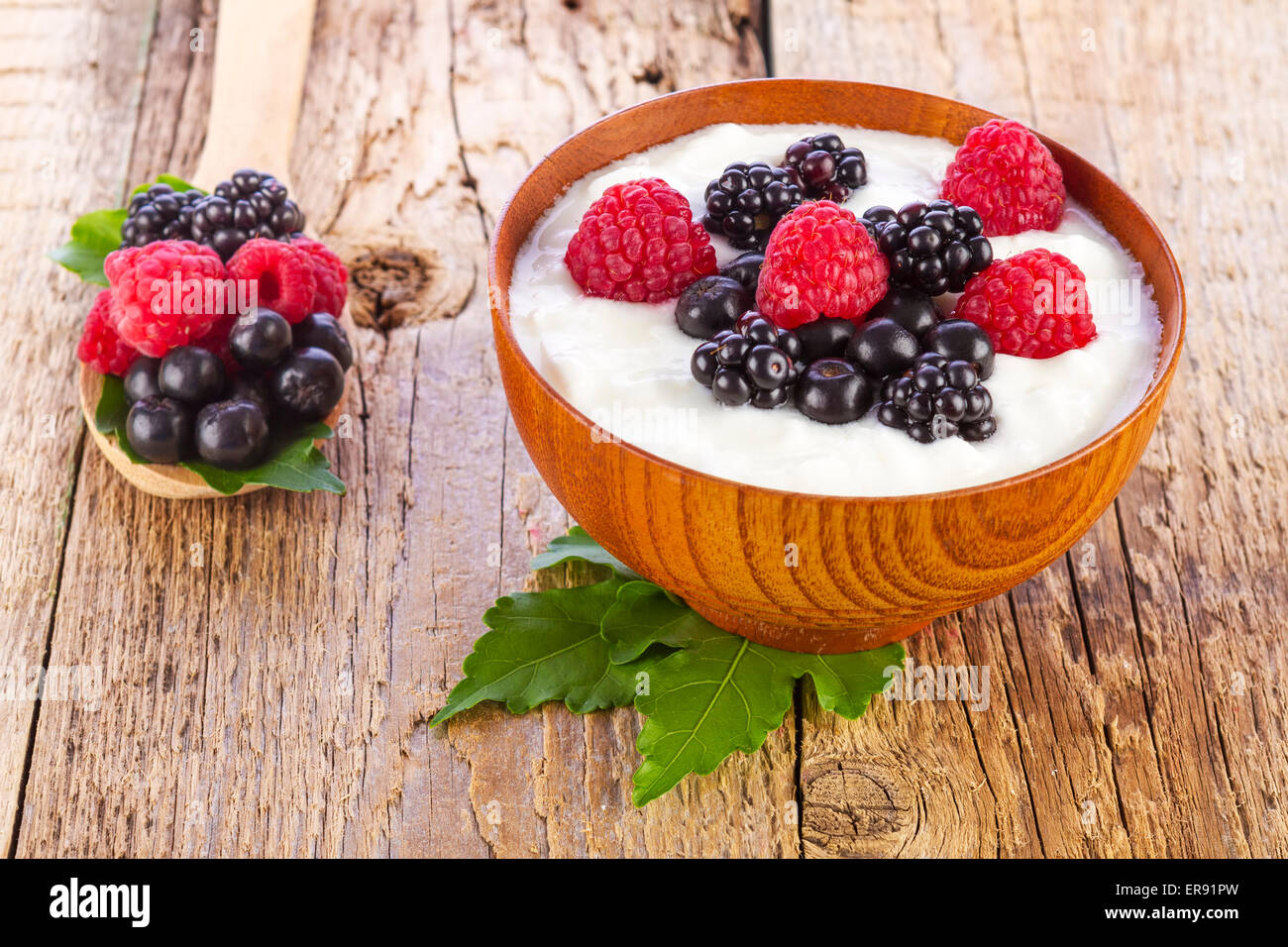 yogurt with wild berries in wooden bowl on wooden background Stock Photo