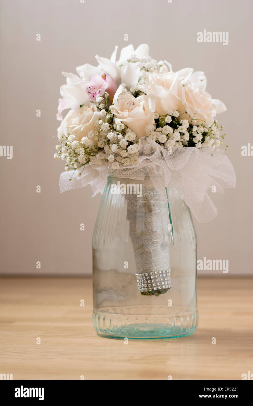 Wedding bouquet with white roses and orchids in glass mug indoor on floor Stock Photo