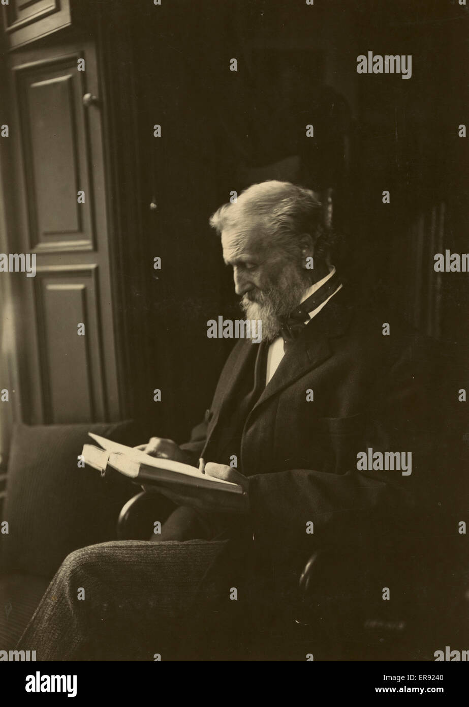 John Muir, seated, reading a book. Date c1912 May 29. Stock Photo