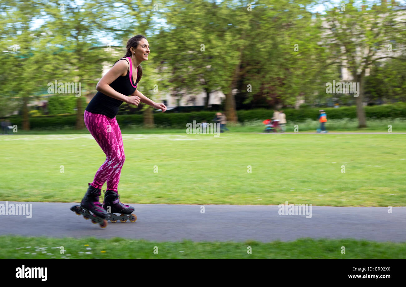 panning shot of a young woman rollerblading in the park Stock Photo
