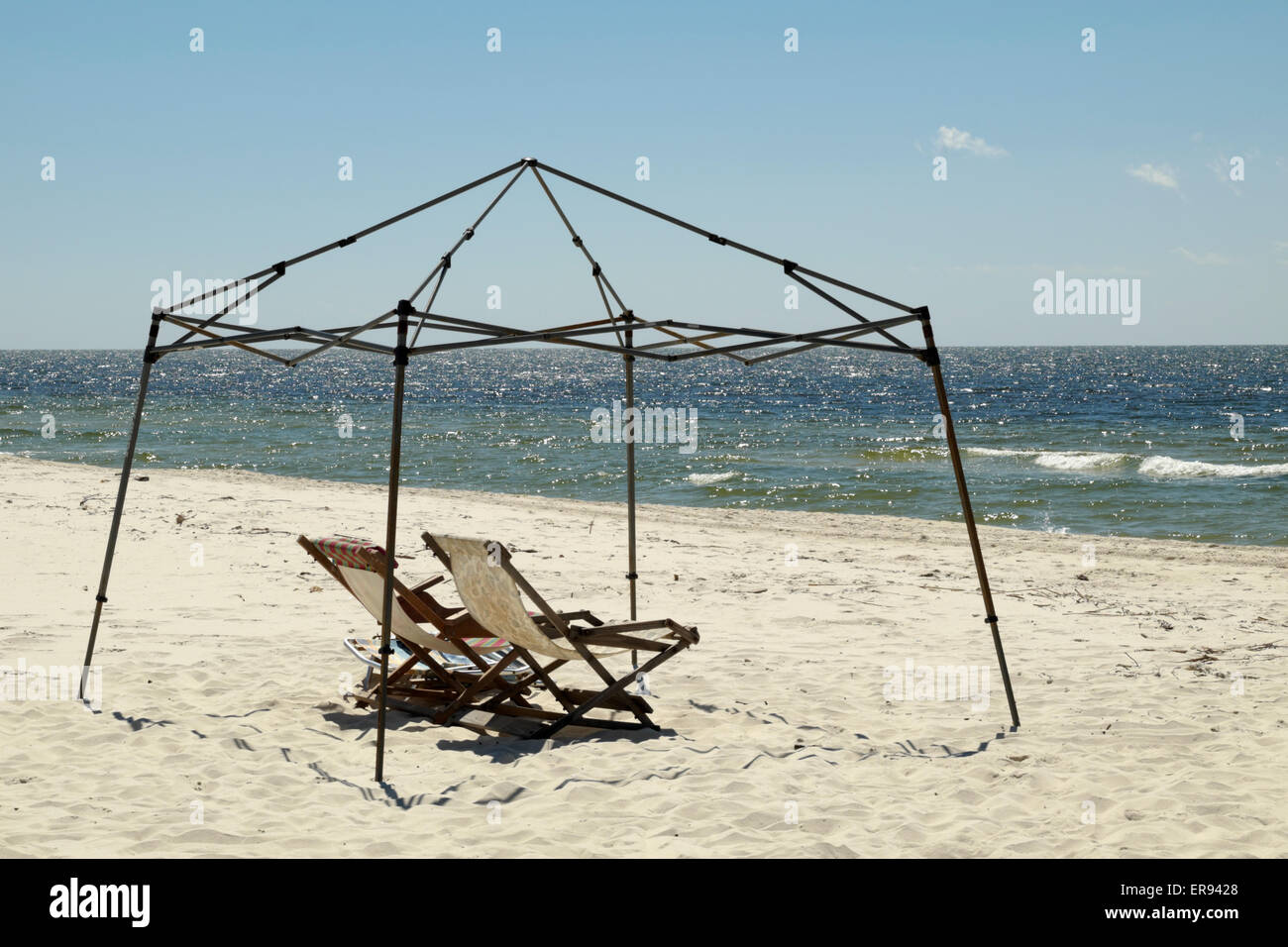 Metal framework for a canopy sits over a pair of chaise lounges on the beach of the Gulf of Mexico in deep south Alabama, USA Stock Photo