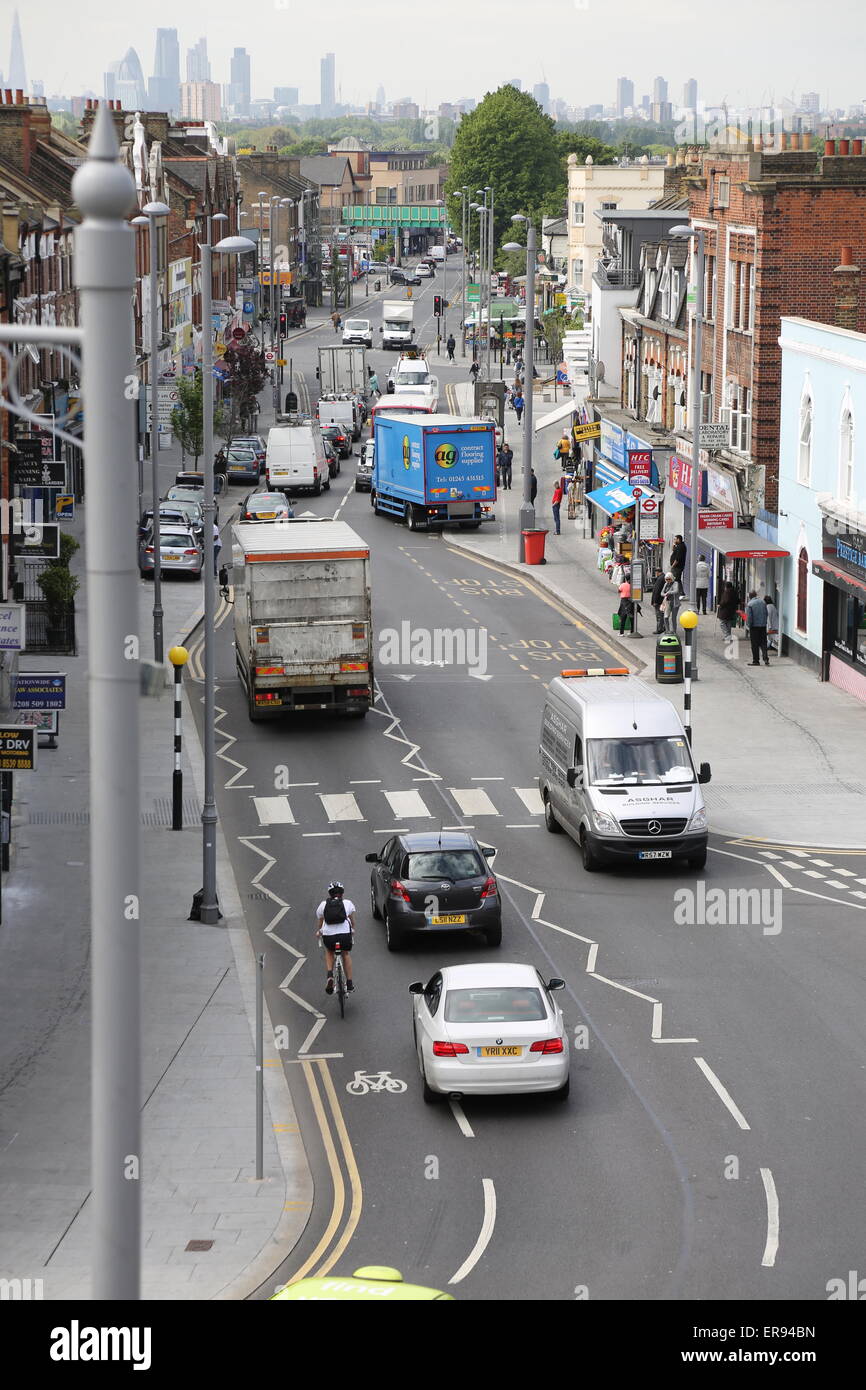 Cars trucks and cyclists on Lee Bridge Road, a busy suburban high street in North London. London city skyline in the background Stock Photo