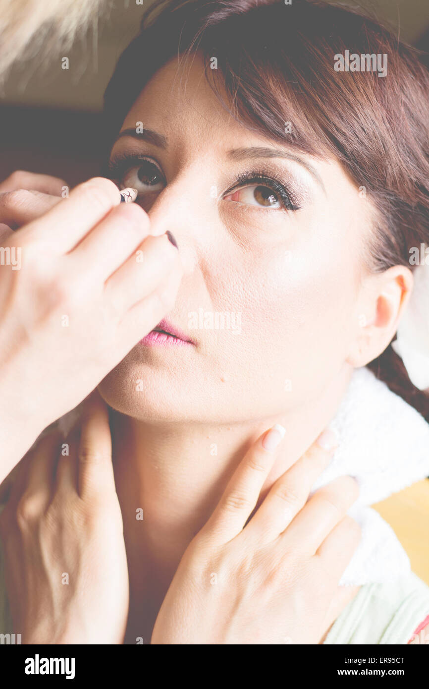 Bride is getting professional make up for her wedding day,putting on mascara. Stock Photo