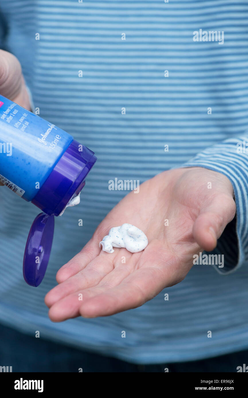 Womans hand holding a facial scrub product with Plastic microbeads