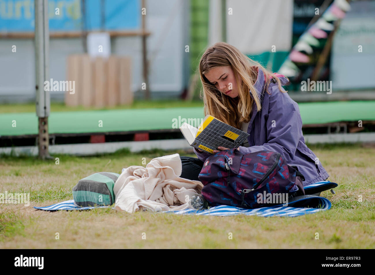 Hay on Wye, UK. Thursday 28 May 2015  Pictured: A young girl sits on the grass  while reading a book  at the Hay Festival RE: The Hay Festival takes place in Hay on Wye, Powys, Wales Stock Photo