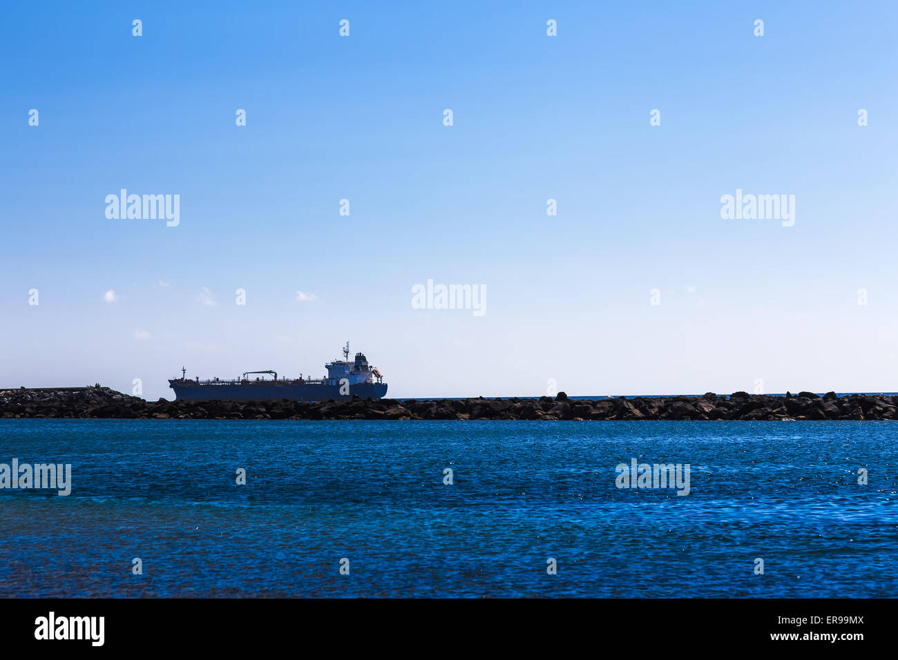 Cargo ship on the water. View from shore through breakwater Stock Photo
