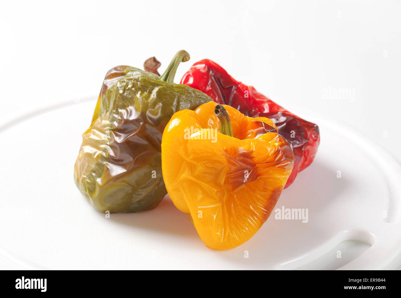 Three roasted bell peppers on a cutting board Stock Photo - Alamy