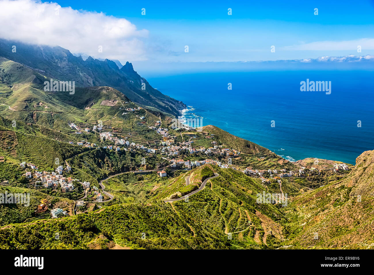 Mountain and clouds with small city or village and sky horizon landscape near the coast or shore of Atlantic ocean in Tenerife Stock Photo