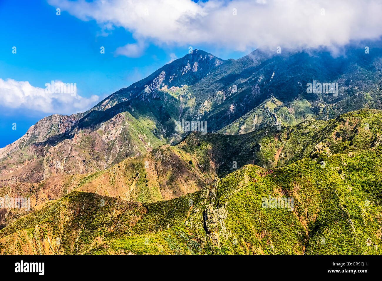 Green rocks with white clouds on blue sky landscape in Tenerife island