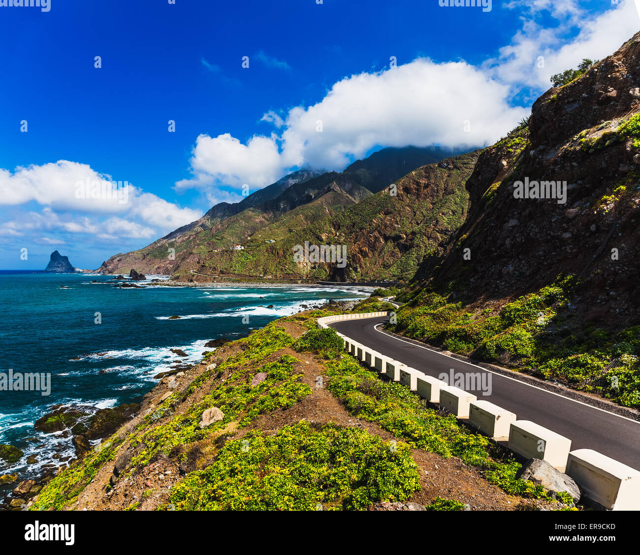 Asphalt road near coast of Atlantic ocean with mountains and blue sky with clouds in Tenerife Canary island, Spain at spring Stock Photo