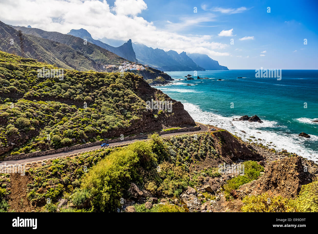 Road near coast of Atlantic ocean with mountains or rocks and blue sky with clouds and skyline or horizon in Tenerife Canary Stock Photo