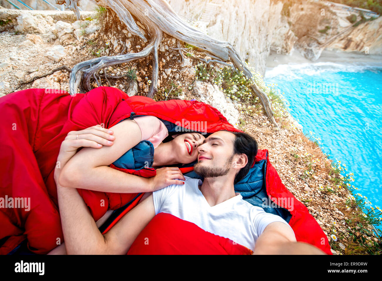 Young couple in sleeping bags near the sea Stock Photo
