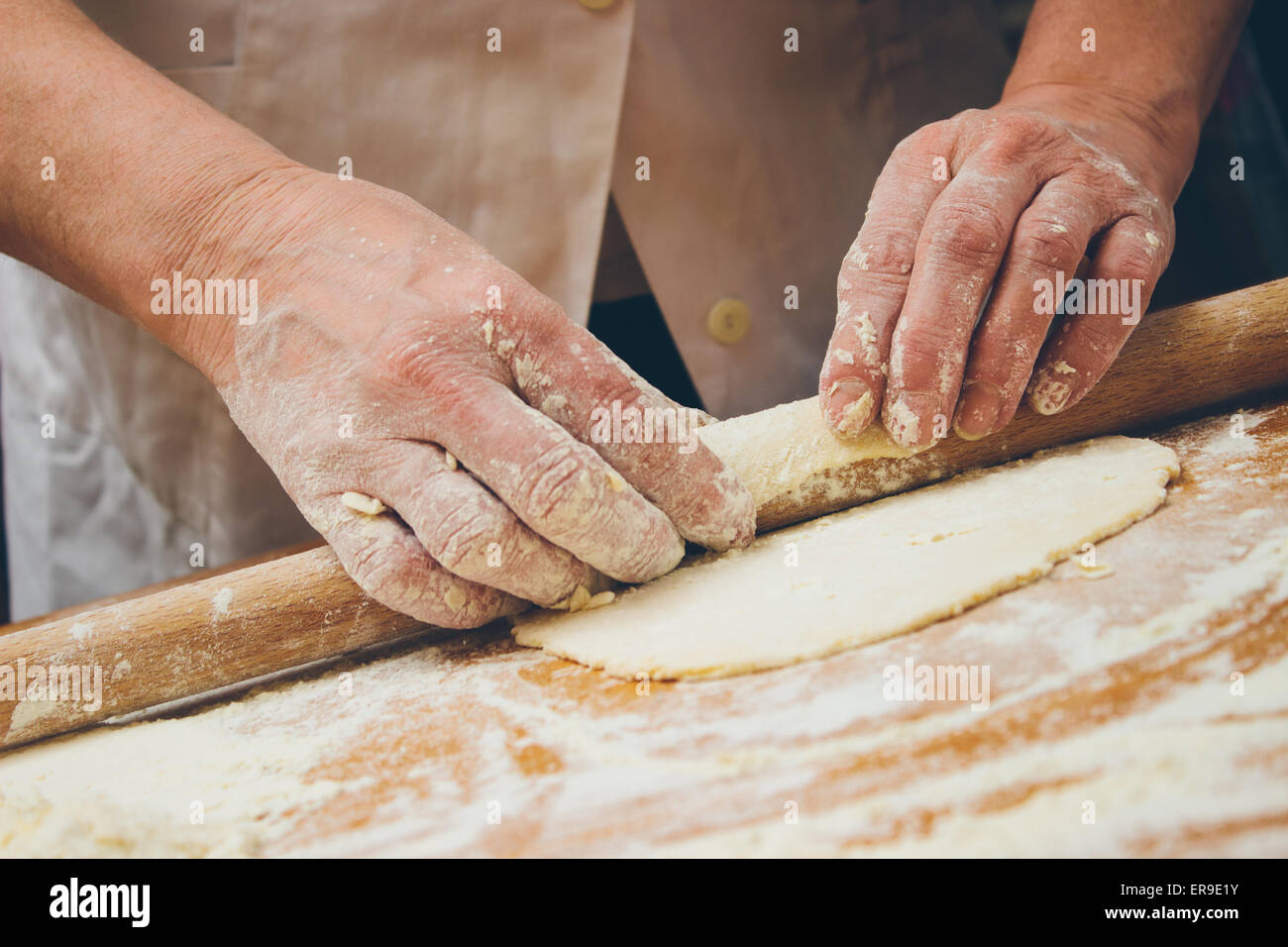 Close up photo of baker kneading dough with a rolling pin. Retro styled