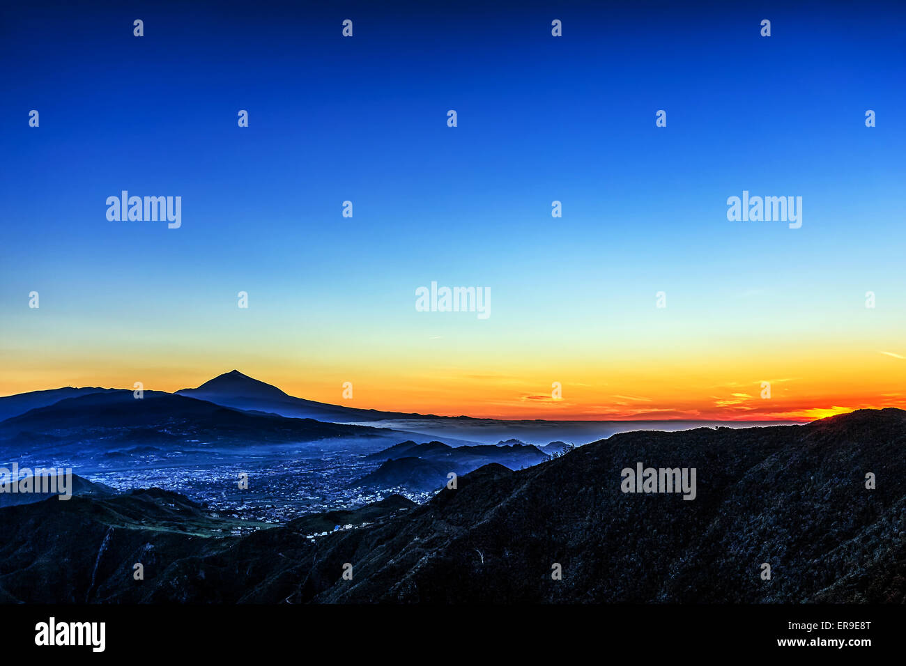 Sunset in mountains and blue sky with fog and Teide volcano on background in Tenerife Canary island, Spain Stock Photo