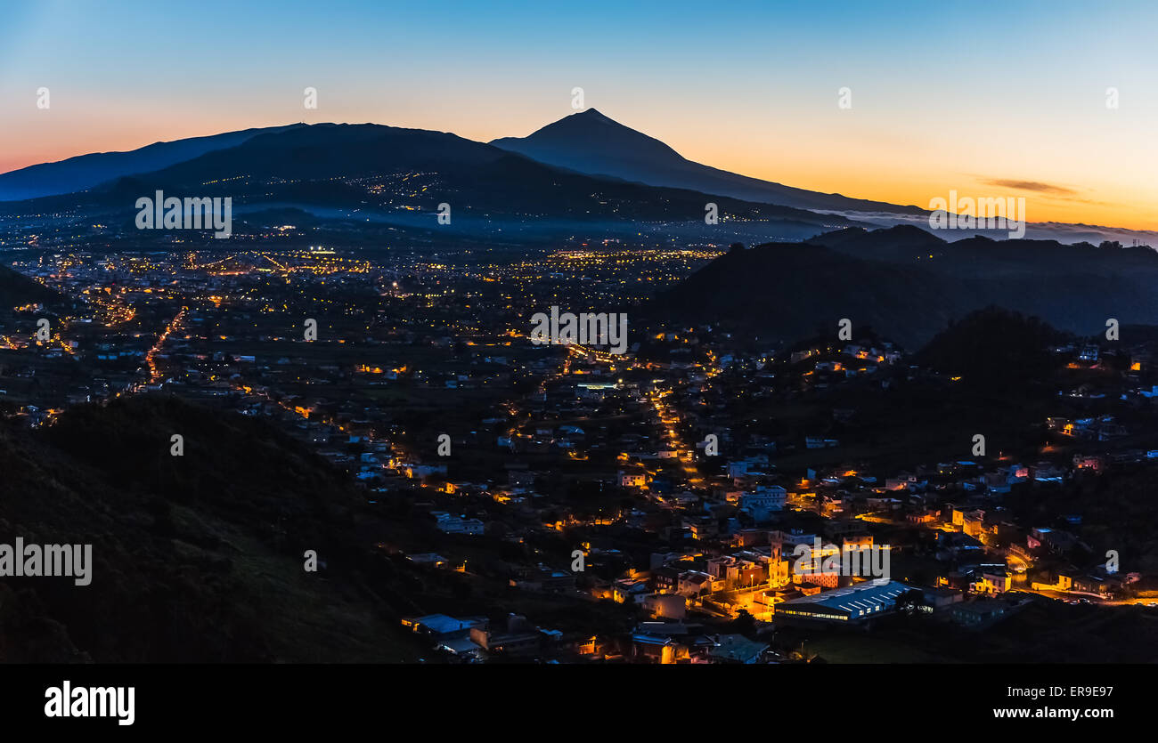 City with illumination after sunset at evening in mountains with blue sky and Teide volcano on background panorama landscape Stock Photo