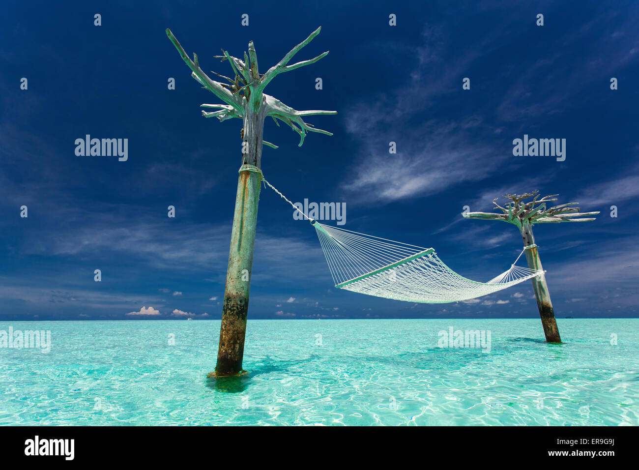 Empty over-water hammock in the middle of tropical lagoon in Maldives Stock Photo