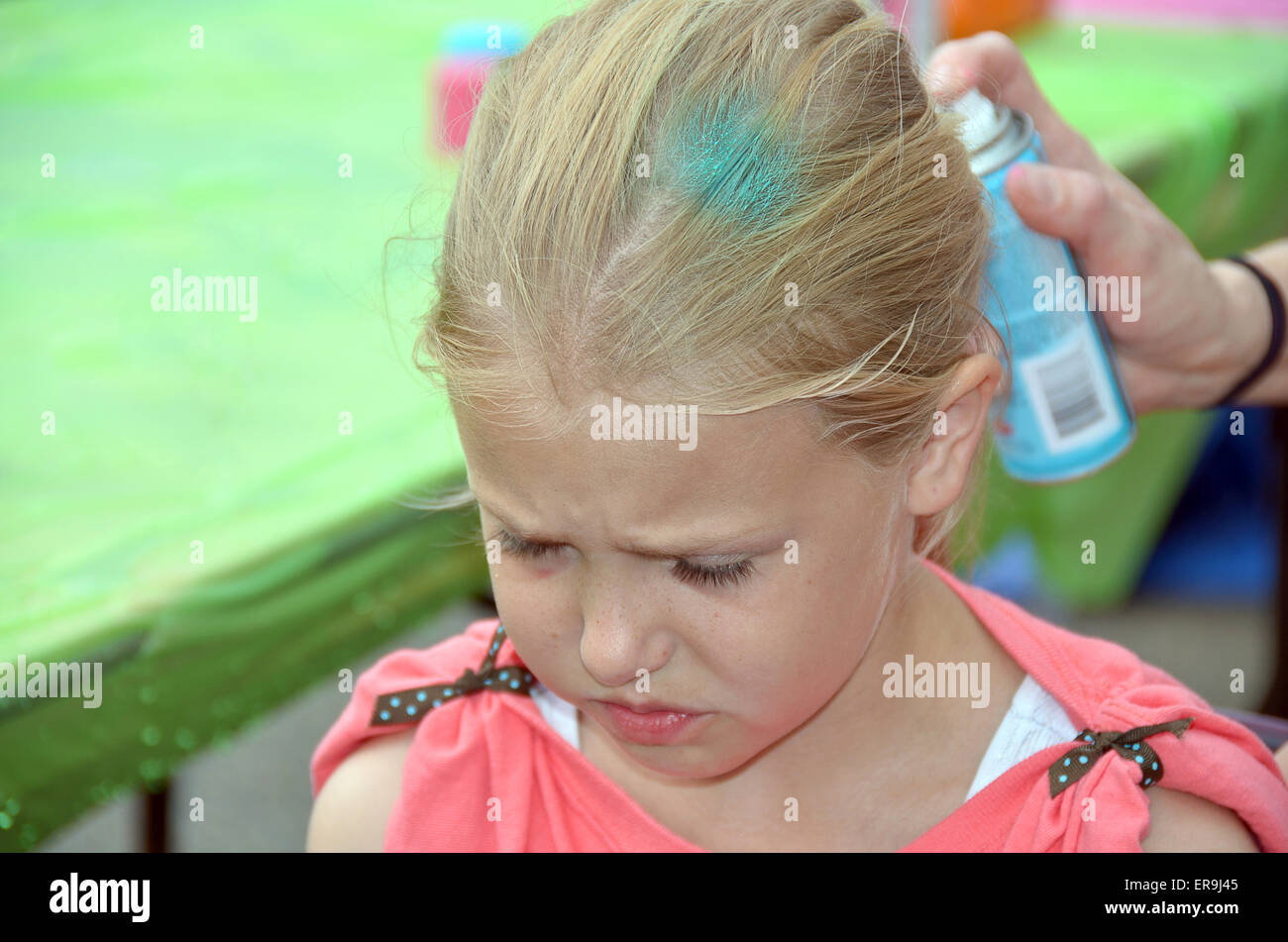 Young Caucasian girl getting her blond hair spray painted. Stock Photo