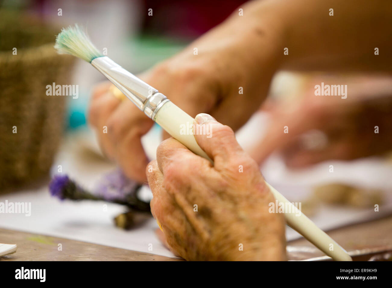 An elderly woman's hand holds a paint brush Stock Photo