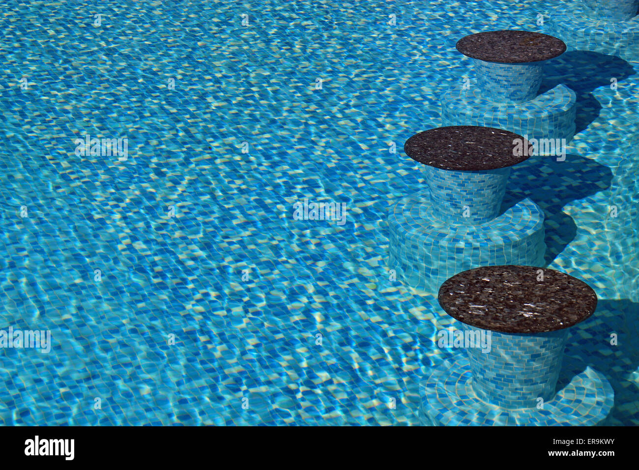 Underwater seats in a swimming pool with clear water and blue mosaic