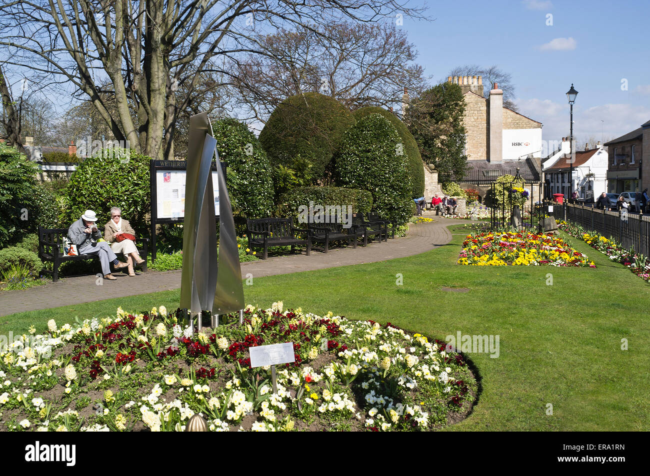 dh Public Gardens WETHERBY WEST YORKSHIRE People sitting on bench flower display park space spring town garden beds uk parks Stock Photo