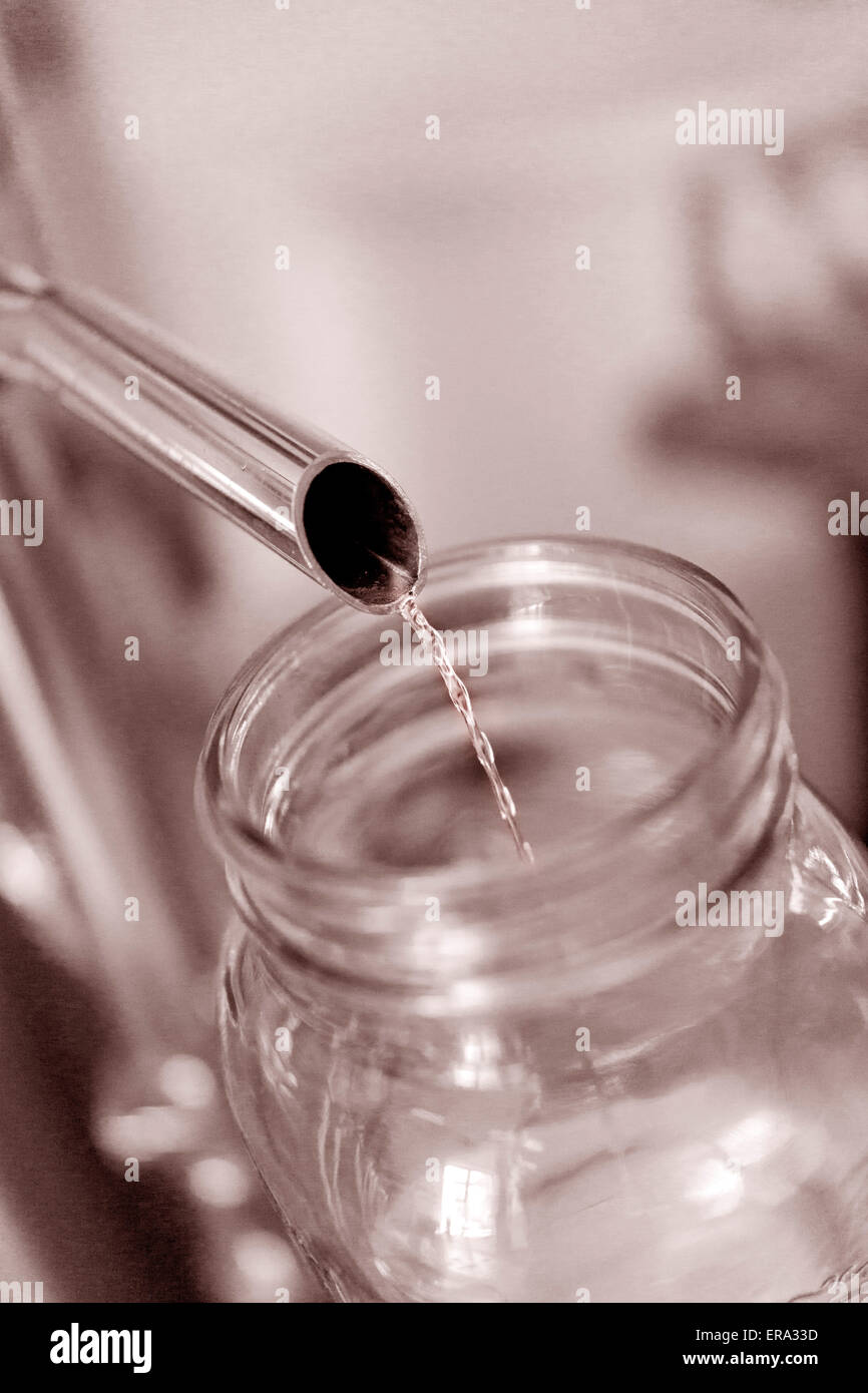 Alcohol pouring into test jar at craft distillery. Vertical Sepia color photograph at Key West Distilling, Florida, USA Stock Photo