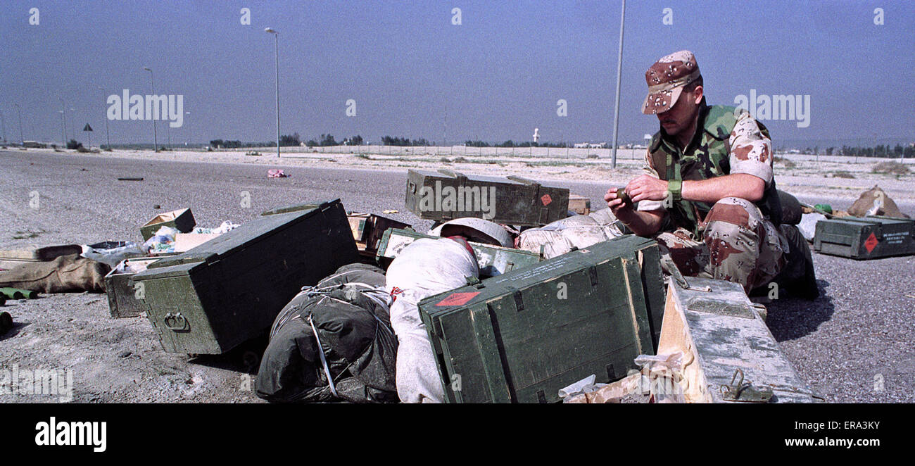 3rd March 1991 A coalition soldier examines a hand grenade, abandoned on a road north of Kuwait City by the fleeing Iraqi Army. Stock Photo