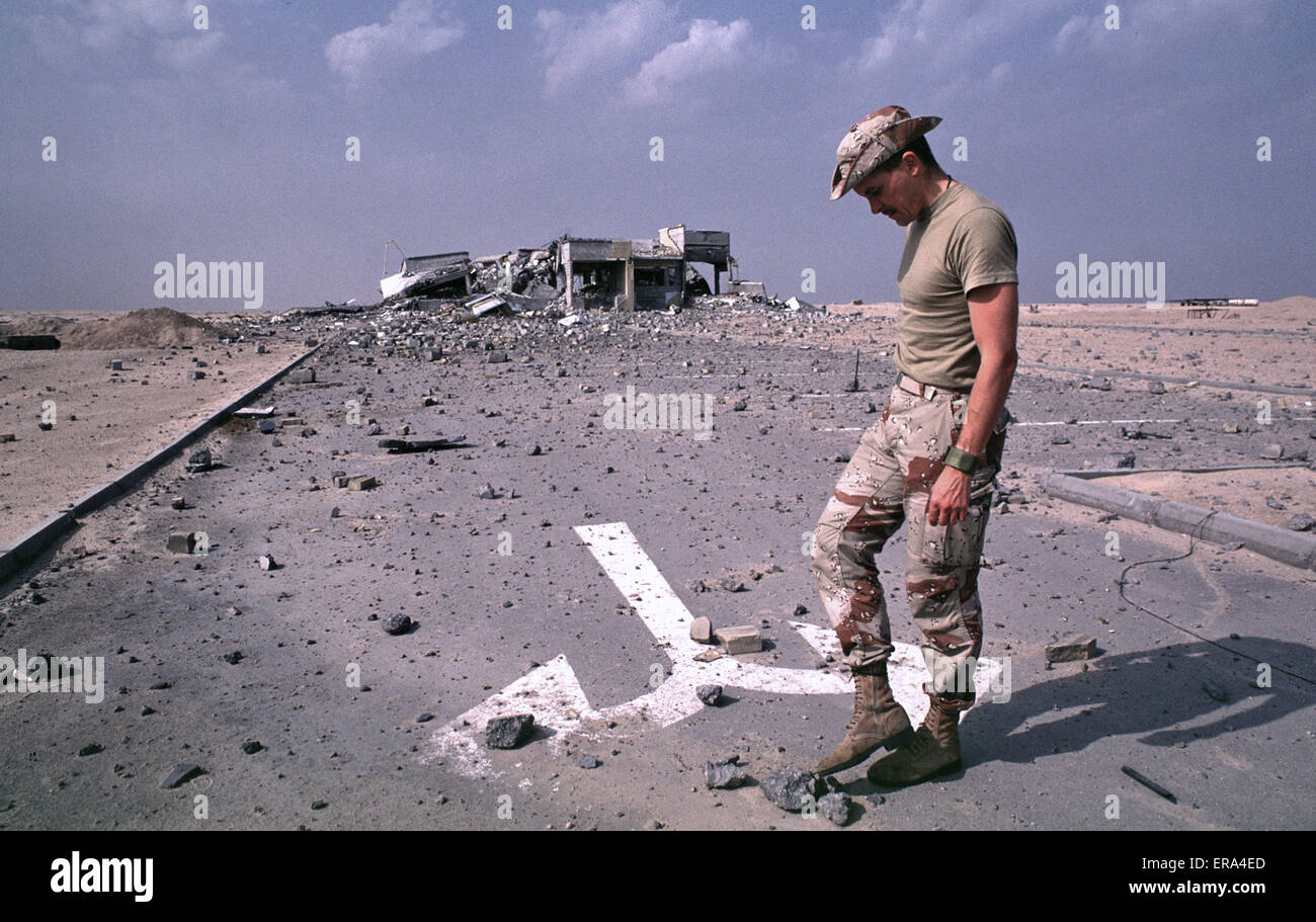 15th March 1991. A coalition soldier examines debris near a bombed toll booth at the bridge to Boubiyan Island in north-east Kuwait. Stock Photo
