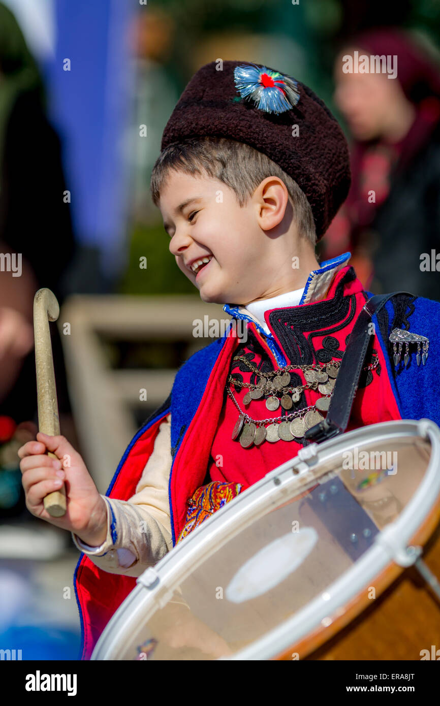 A young Bulgarian folklore musician smiling while drumming during the traditional folklore festival '1000 national costumes' Stock Photo