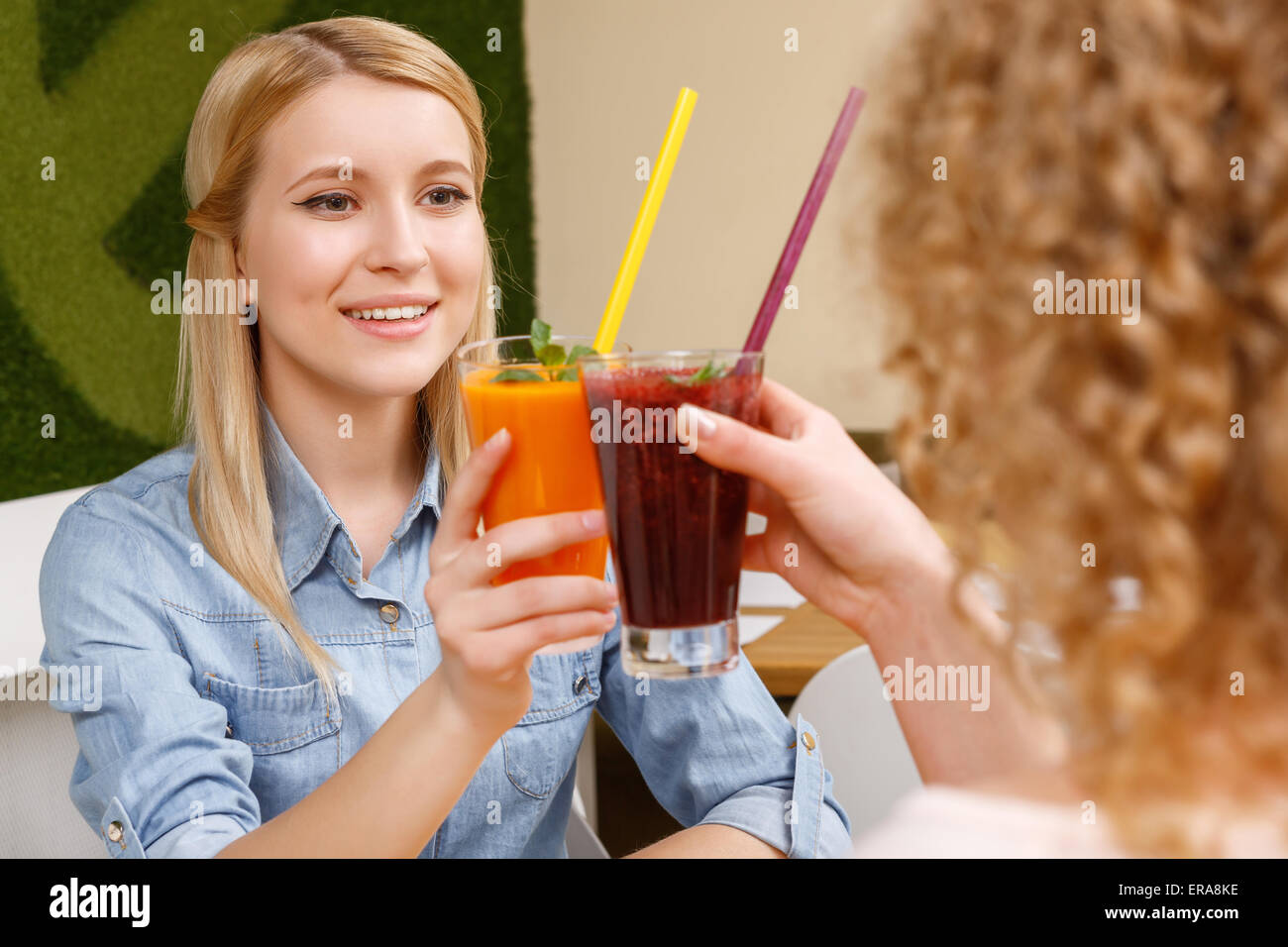 Two women clinking glasses with cocktails in cafe Stock Photo Alamy