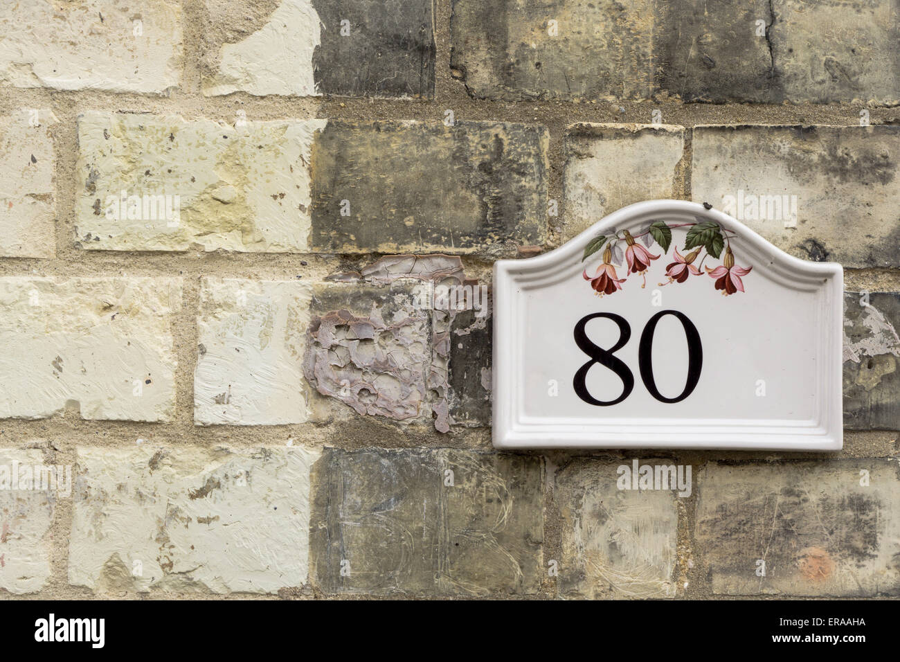Eighty 80 written on a mounted plate on a brick wall closeup Stock