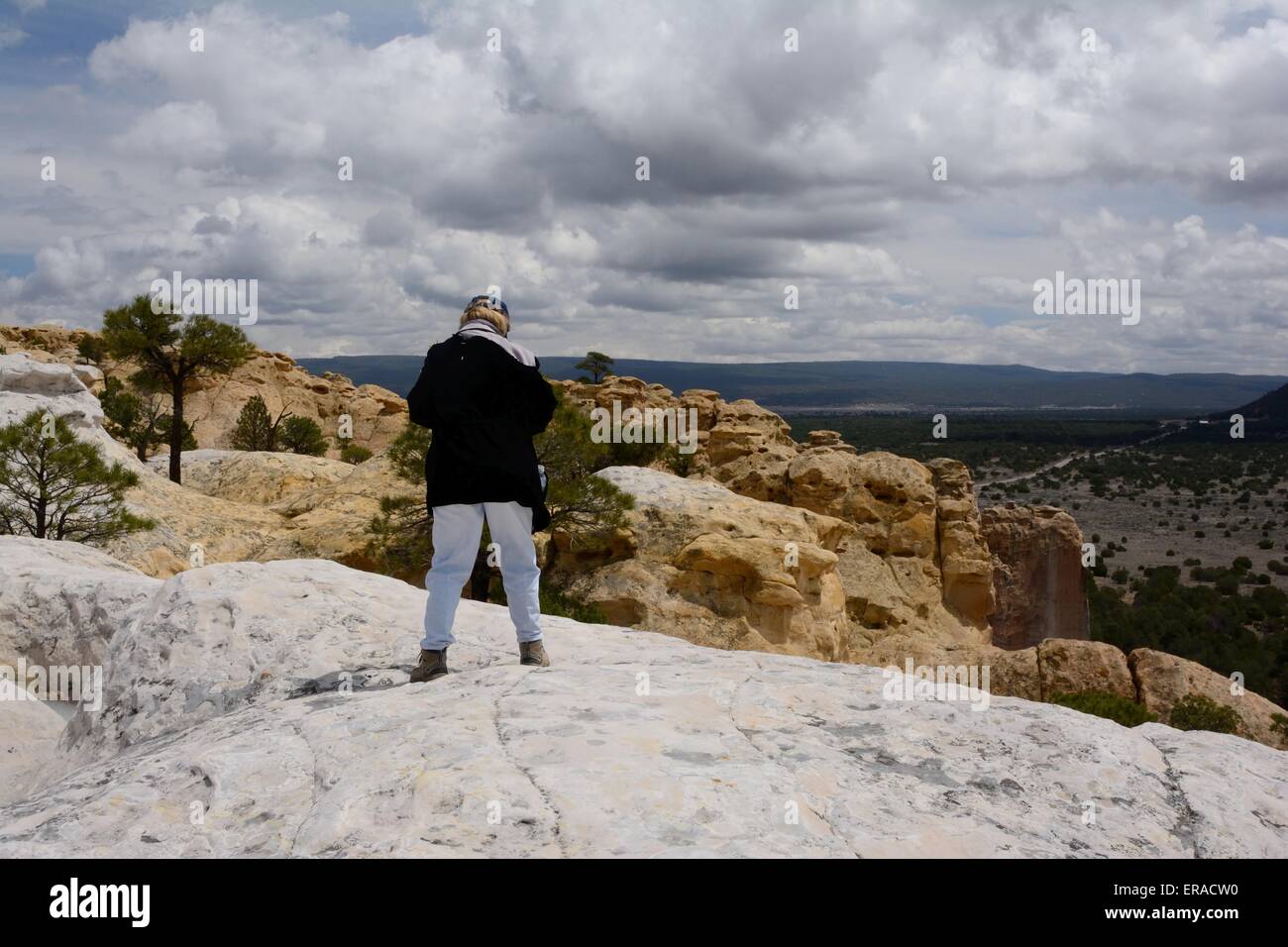 70 year old Senior Citizen on sandstone bluff at El Morro National Monument New Mexico - USA Stock Photo