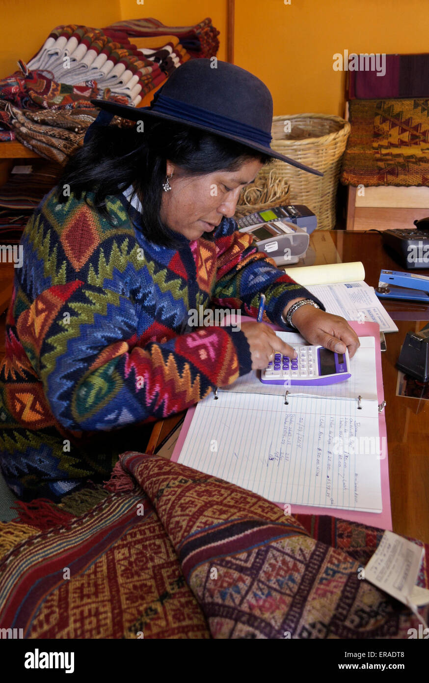 Woman working in shop selling woven textiles, Chinchero, Peru Stock Photo