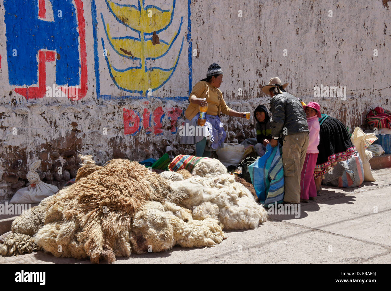 Woman selling chicha (beer) and llama skins on street, Quiquijana (near Cuzco), Peru Stock Photo