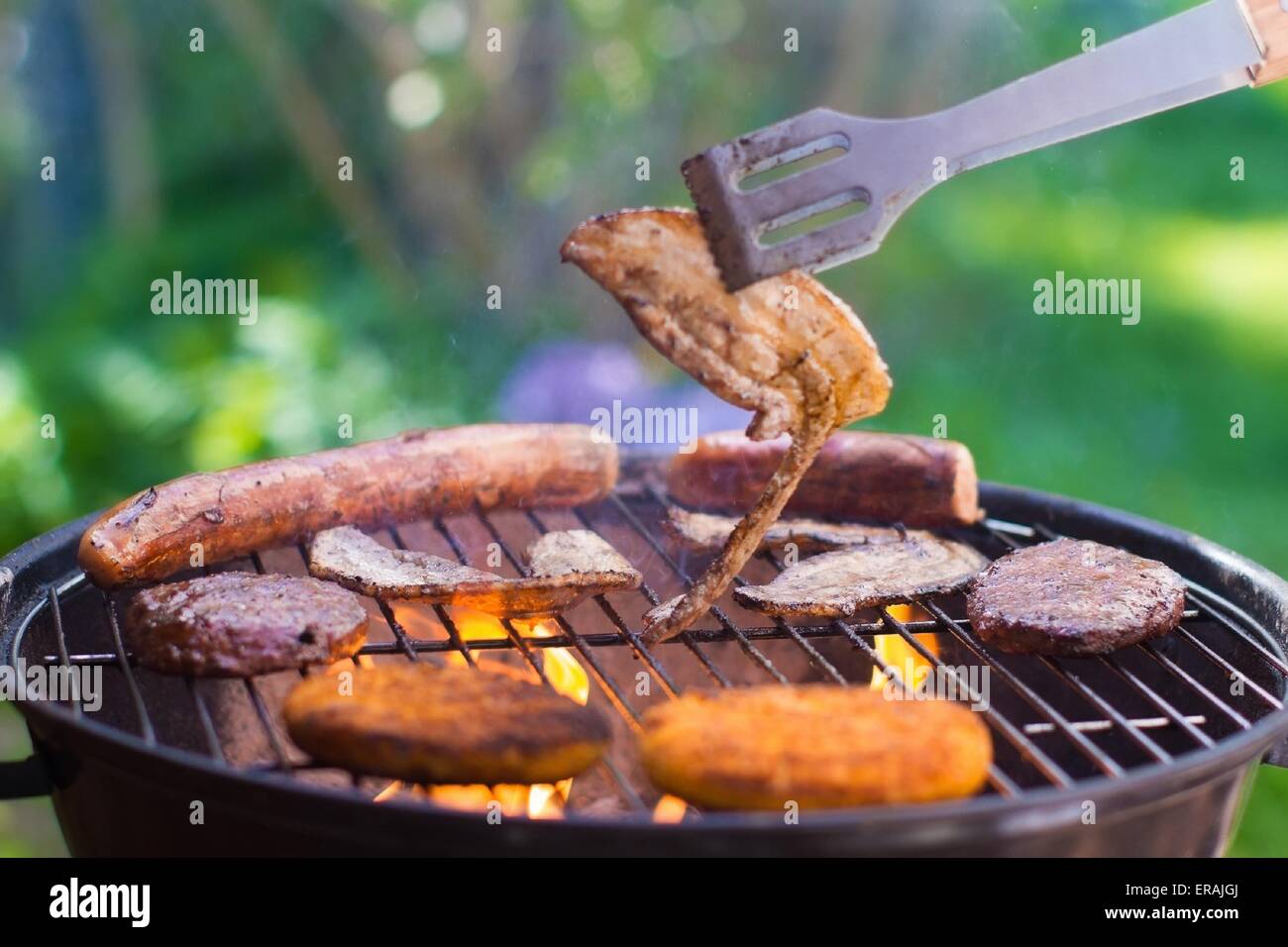 Grilled meat on bbq. Barbecue lunch in the garden. Grill tools. German sausage and steak for outdoor dinner. Stock Photo
