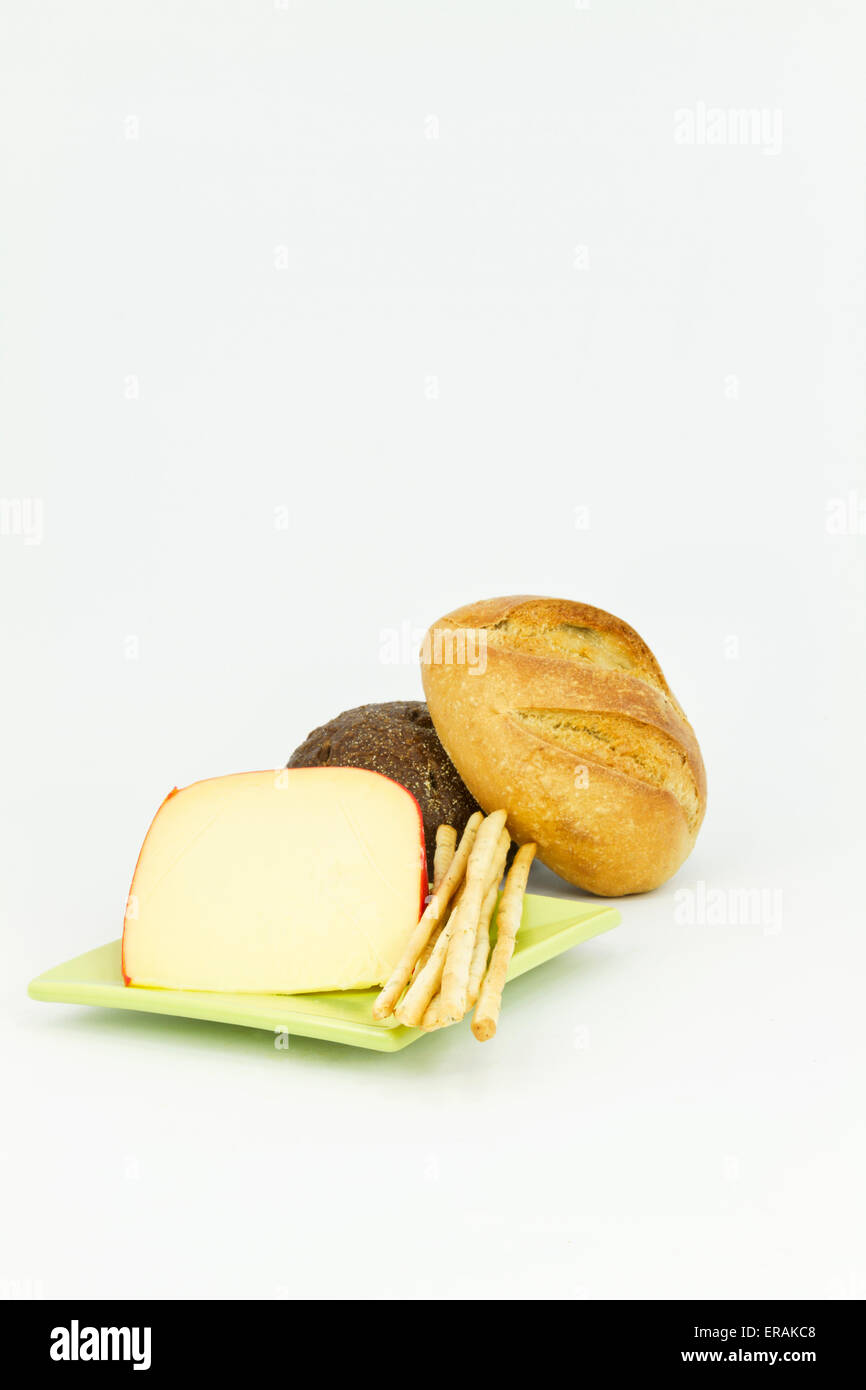 Vertical image with dark and light breads placed with gouda cheese and breadsticks on white background. Stock Photo