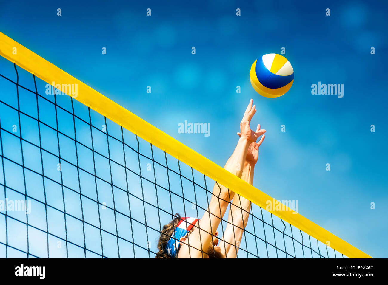 Beachvolley ball player jumps on the net and tries to  blocks the ball Stock Photo
