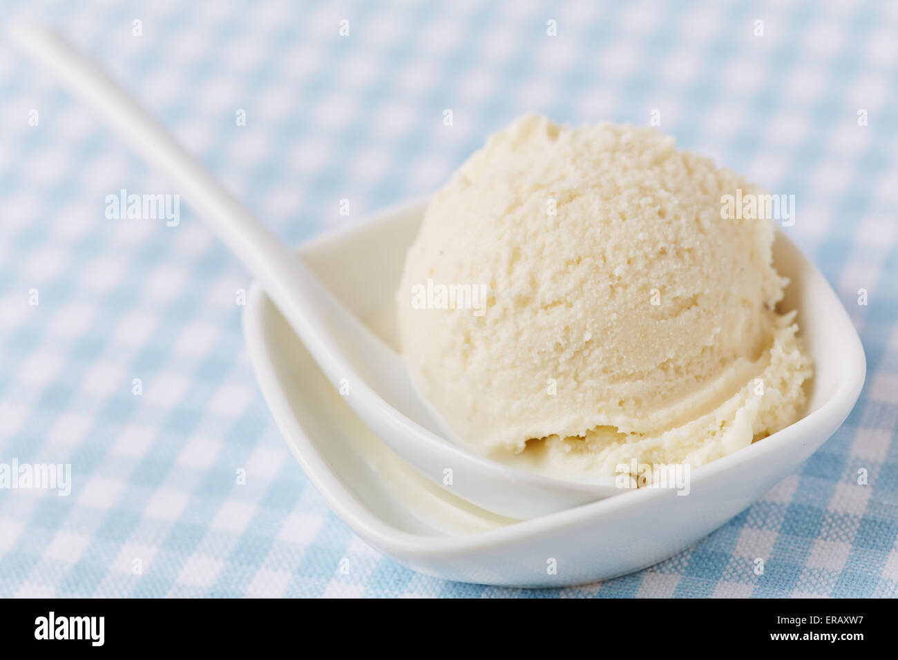 Homemade vanilla ice cream ball in spoon on ice cream container on