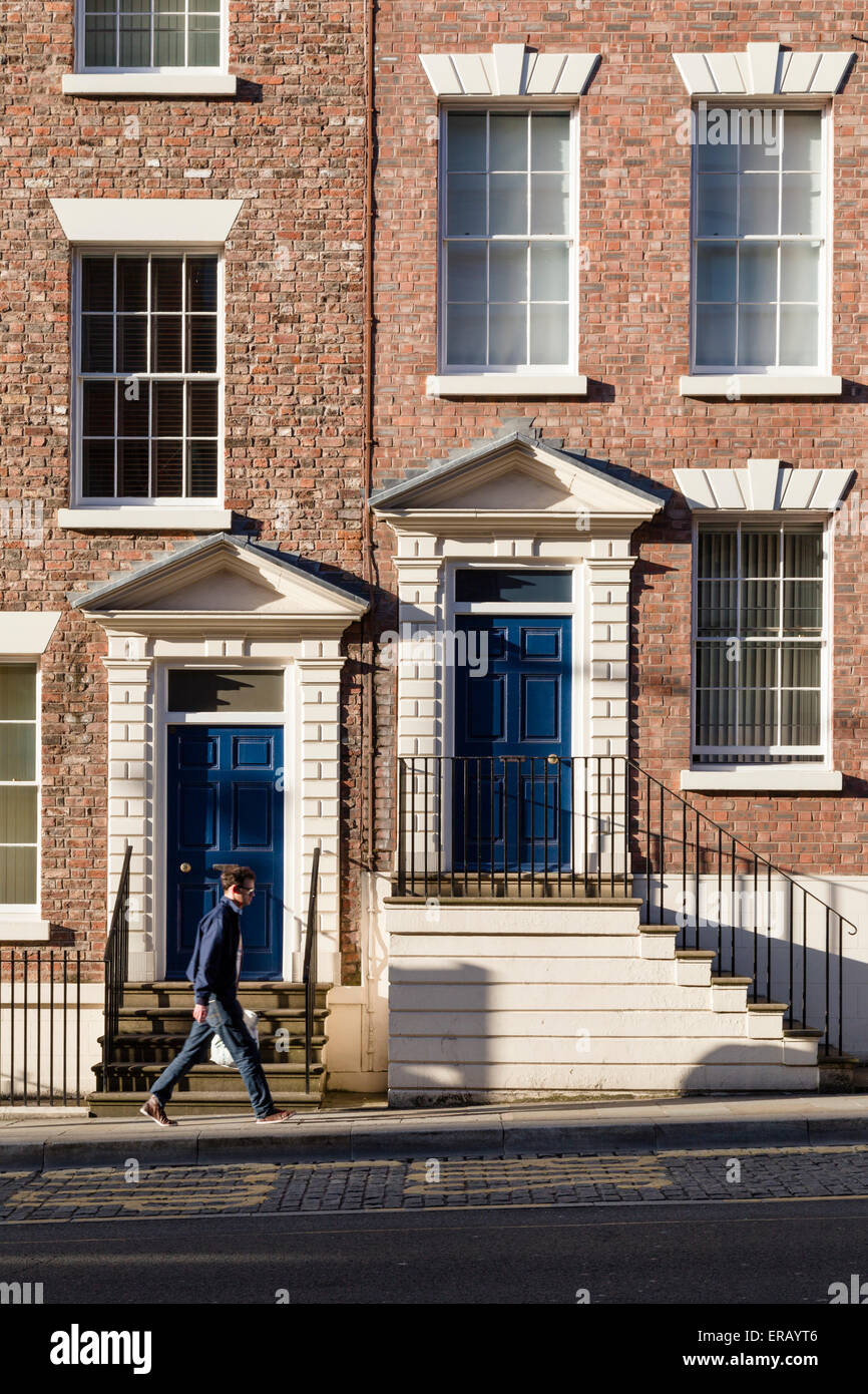 A man walking past two Regency doorcases with steps in Liverpool. Stock Photo