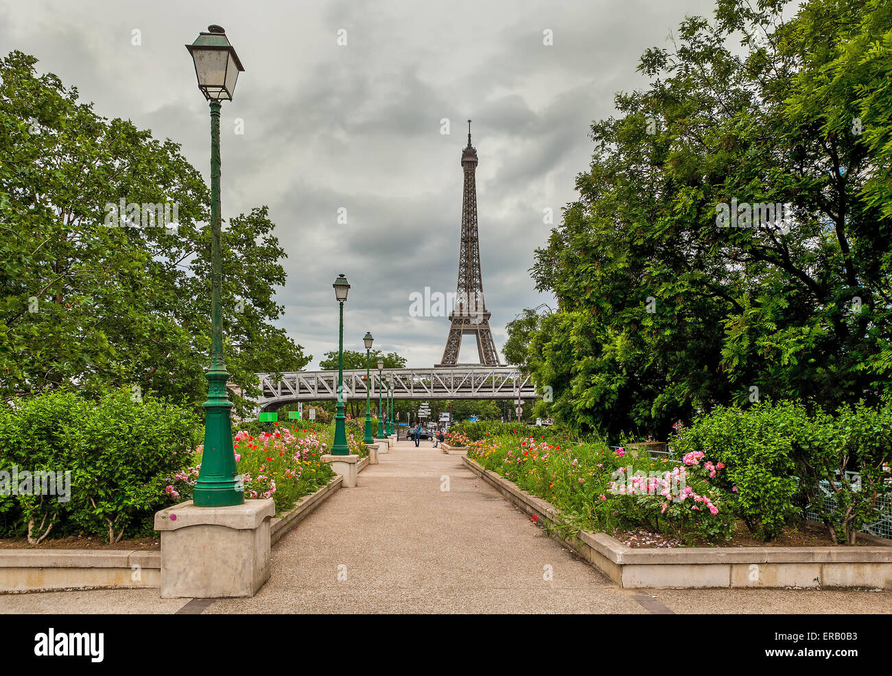 Urban park with green trees, flowers and lampposts as Eiffel Tower on background in Paris, France. Stock Photo