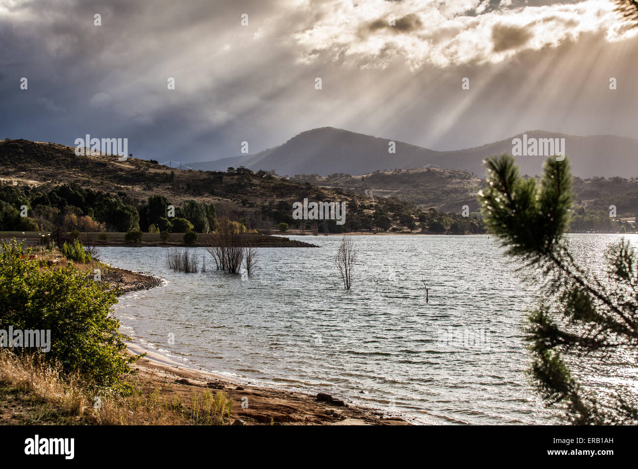 Sun Rays shining through clouds on the Hills of Lake Jindabyne, Australia. Stock Photo