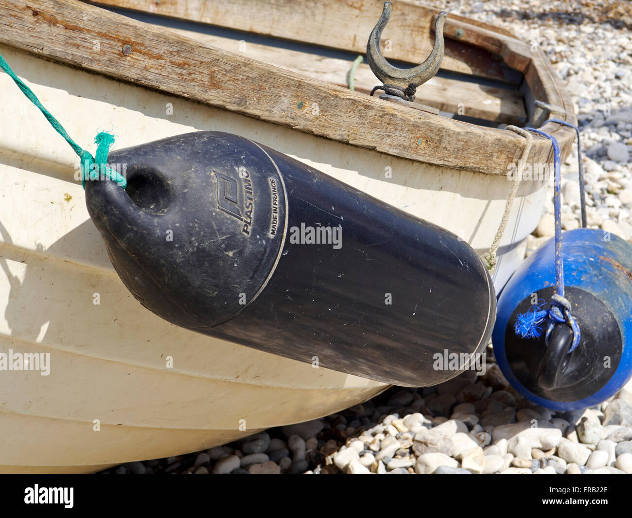 Black and blue fenders on the side of a small fibreglass rowing boat