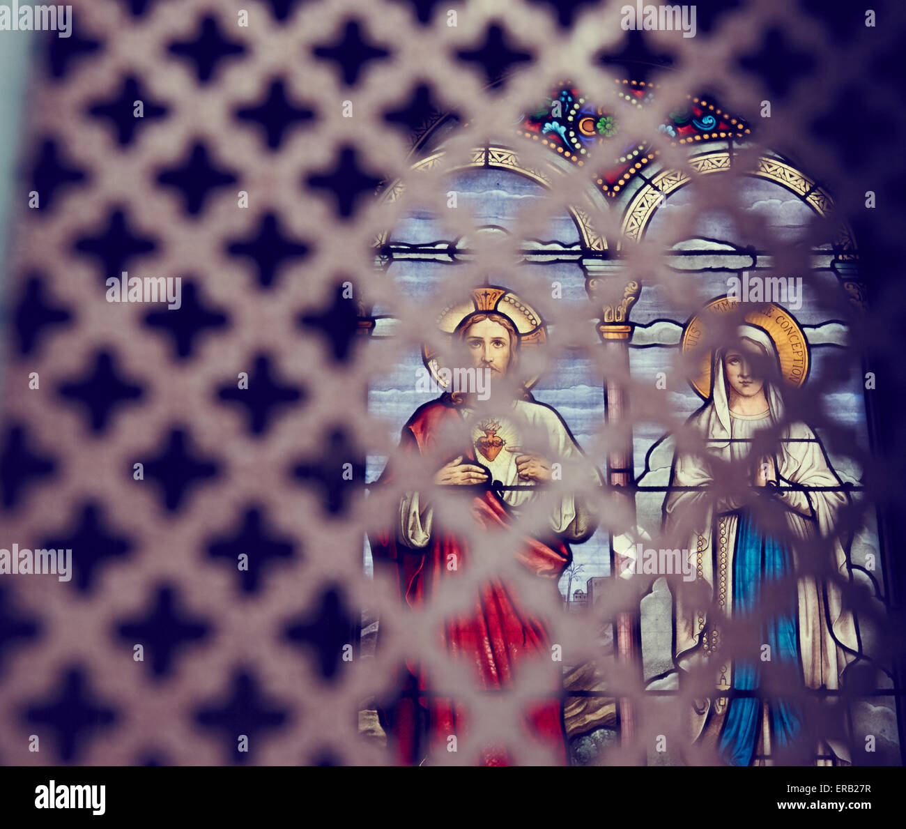 Stained glass window depicting Jesus and Mary seen through lattice of ...