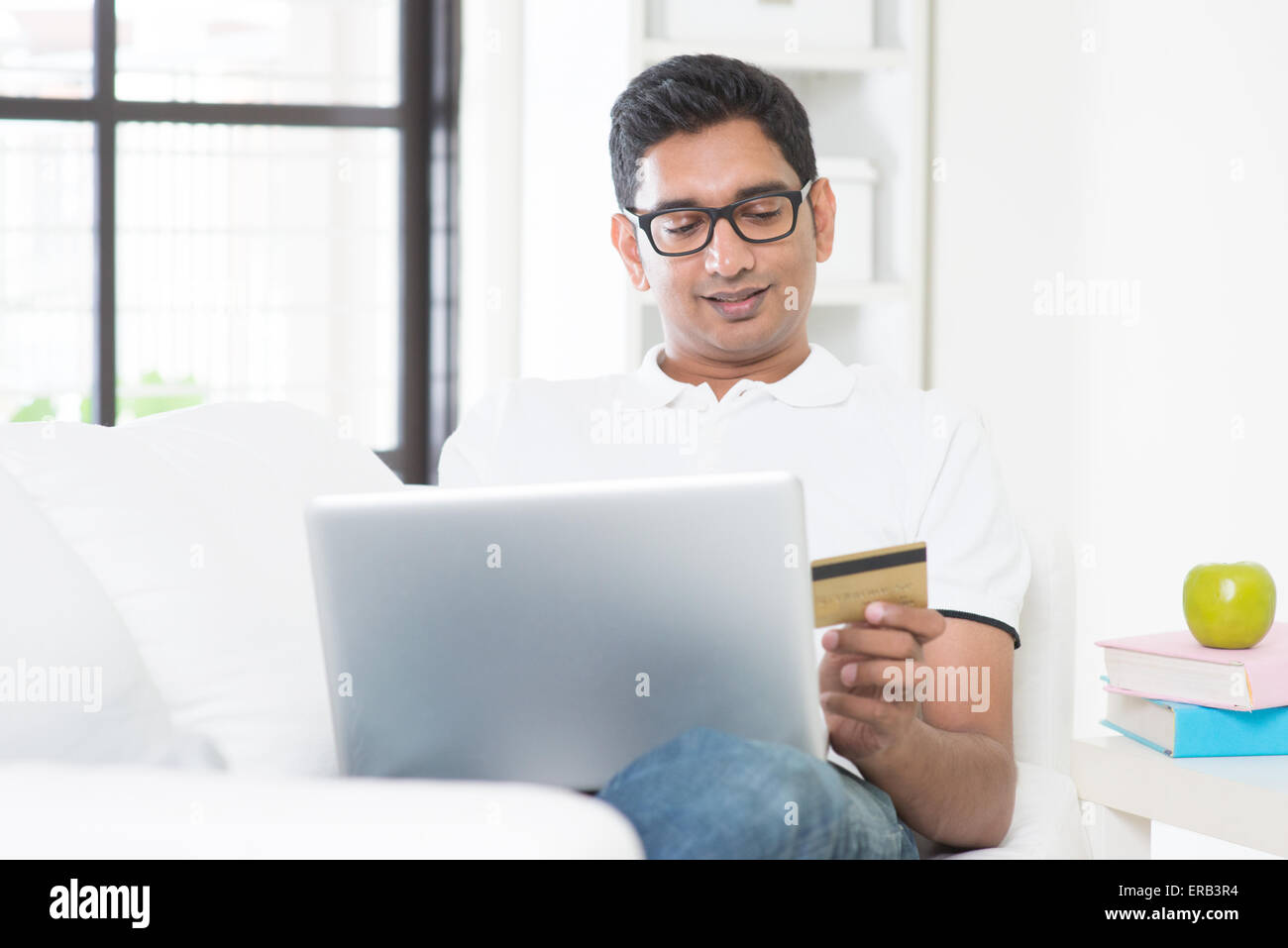 Indian guy online shopping hand holding credit card with laptop