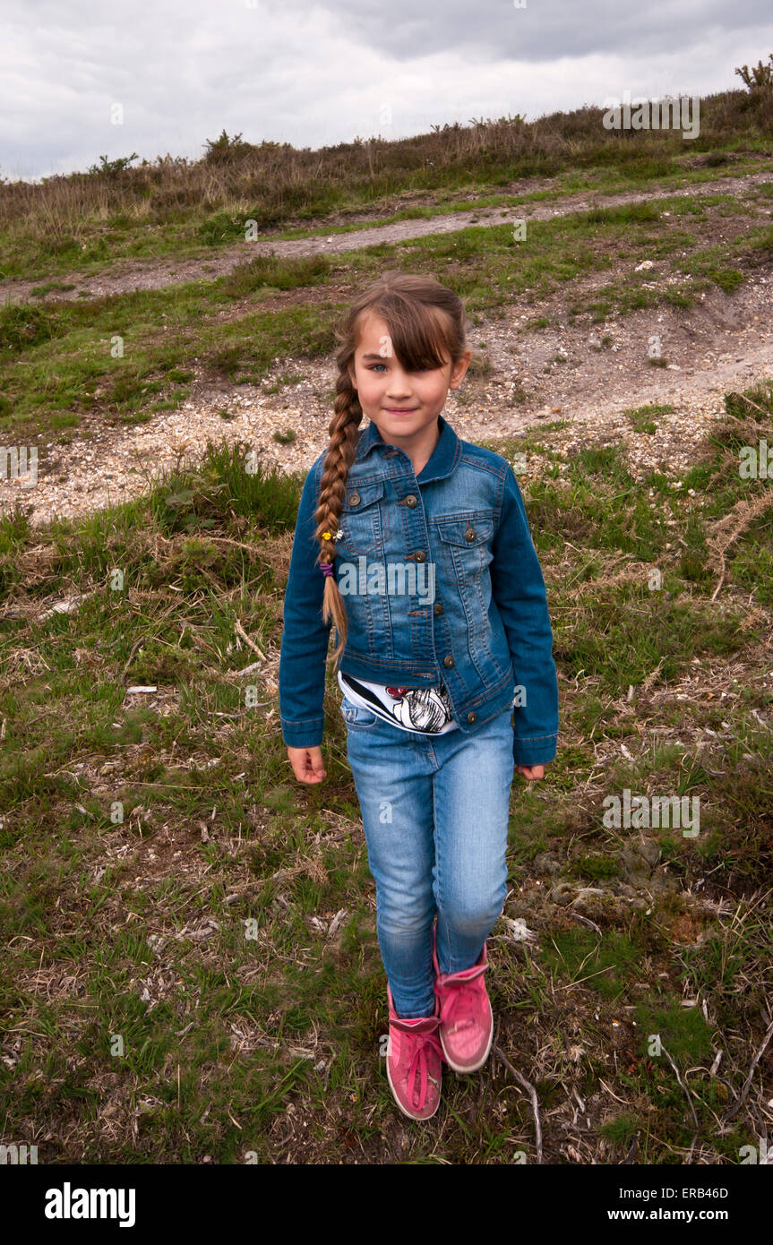 6 Year Old Girl Wearing Denims Jeans With Long Hair In A Ponytail Outdoors Stock Photo