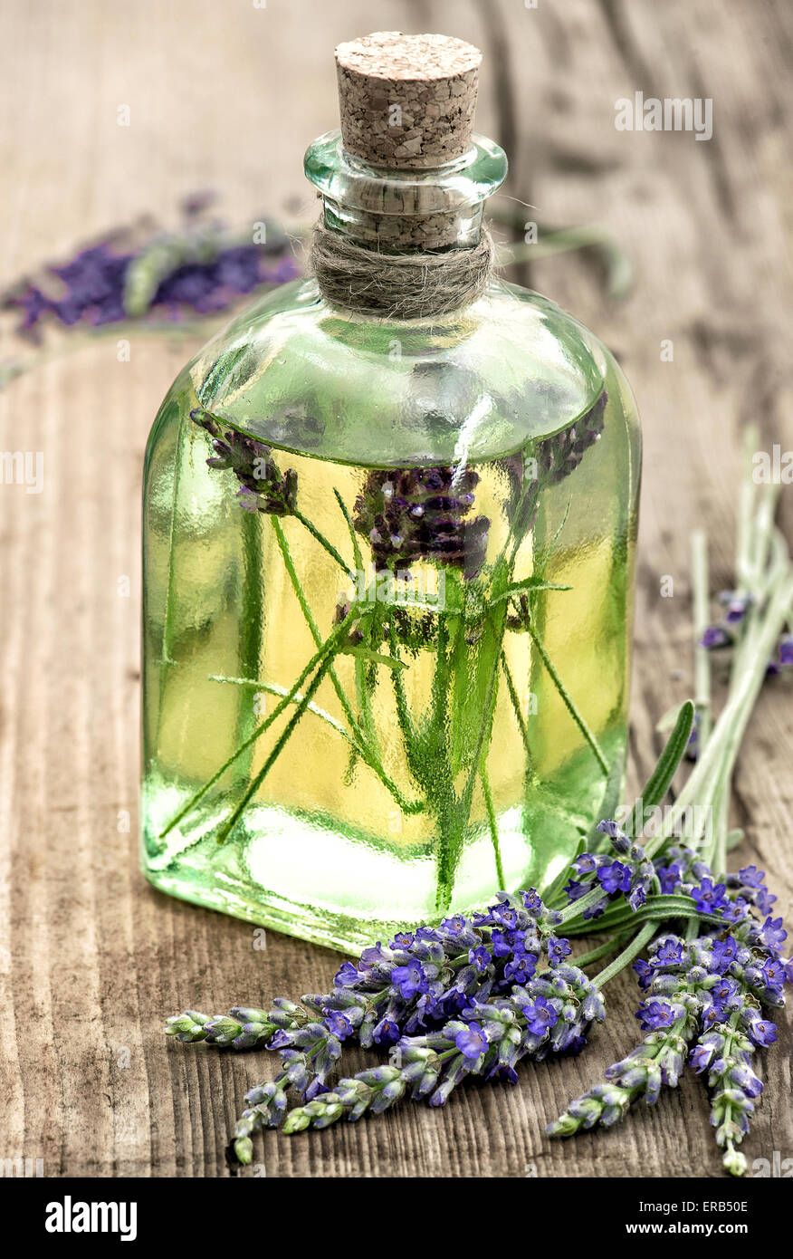 Lavender oil with fresh flowers on wooden background. Healthy herbs. Selective focus Stock Photo