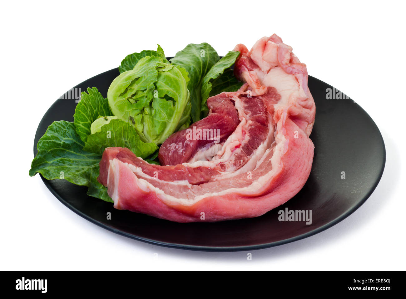 Raw streaky pork on black plate, isolated on white background and clipping path Stock Photo