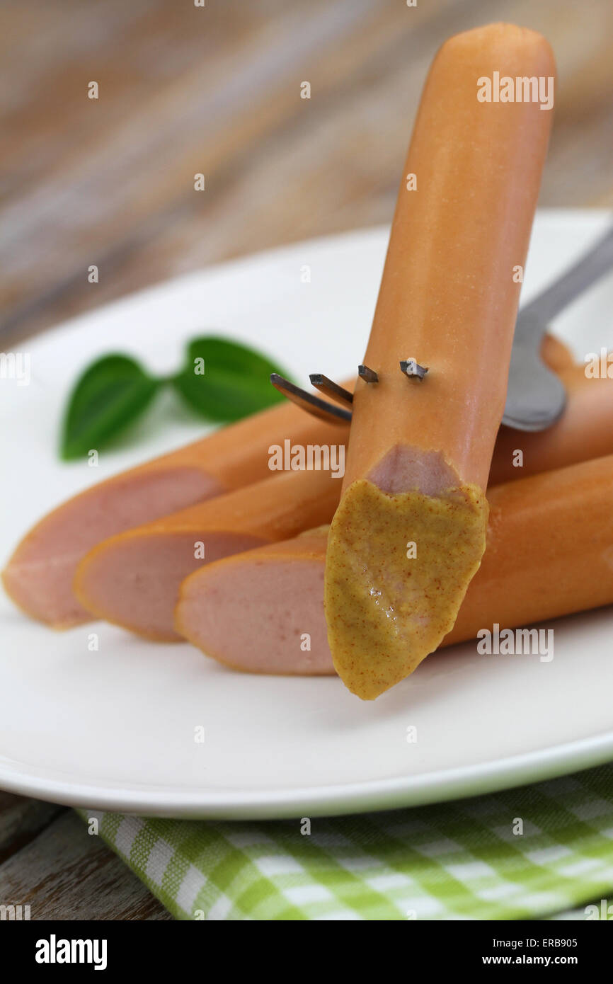 Frankfurter with mustard on fork, closeup Stock Photo