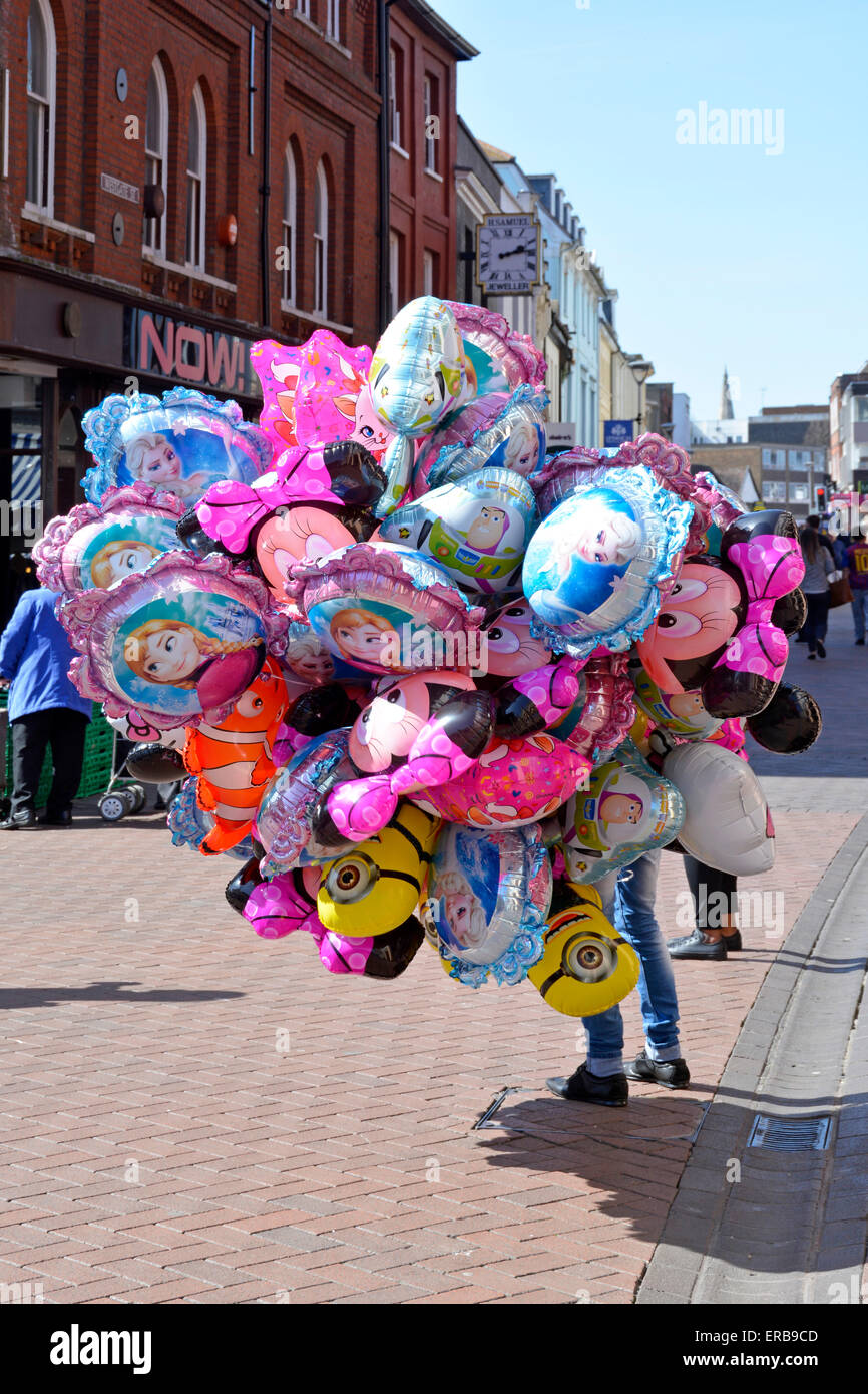 Ipswich town centre market stalls area with street seller holding large cluster of gas filled balloons Stock Photo